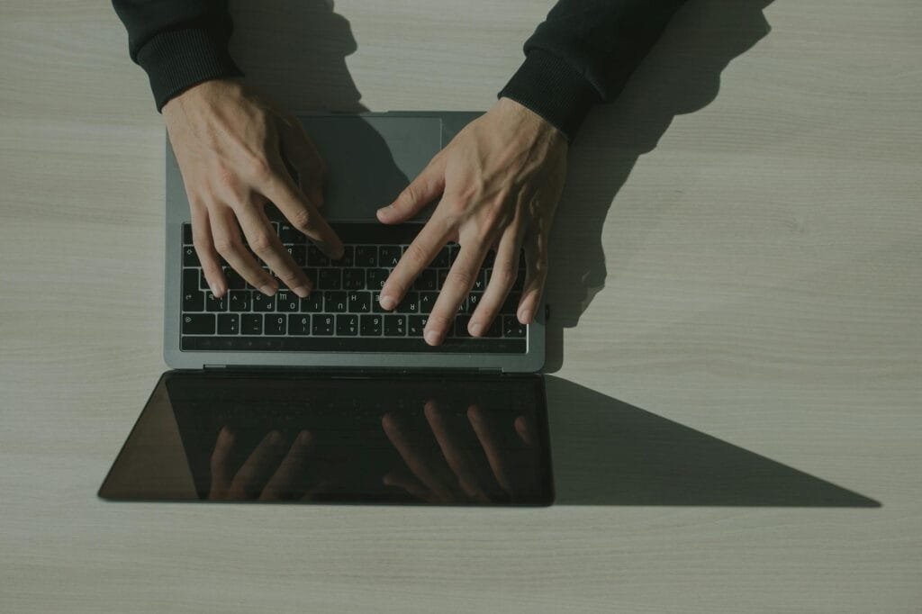 Hands type on a laptop at a desk, reflecting the practical skills and hands-on work behind entry level cybersecurity jobs and junior security roles.